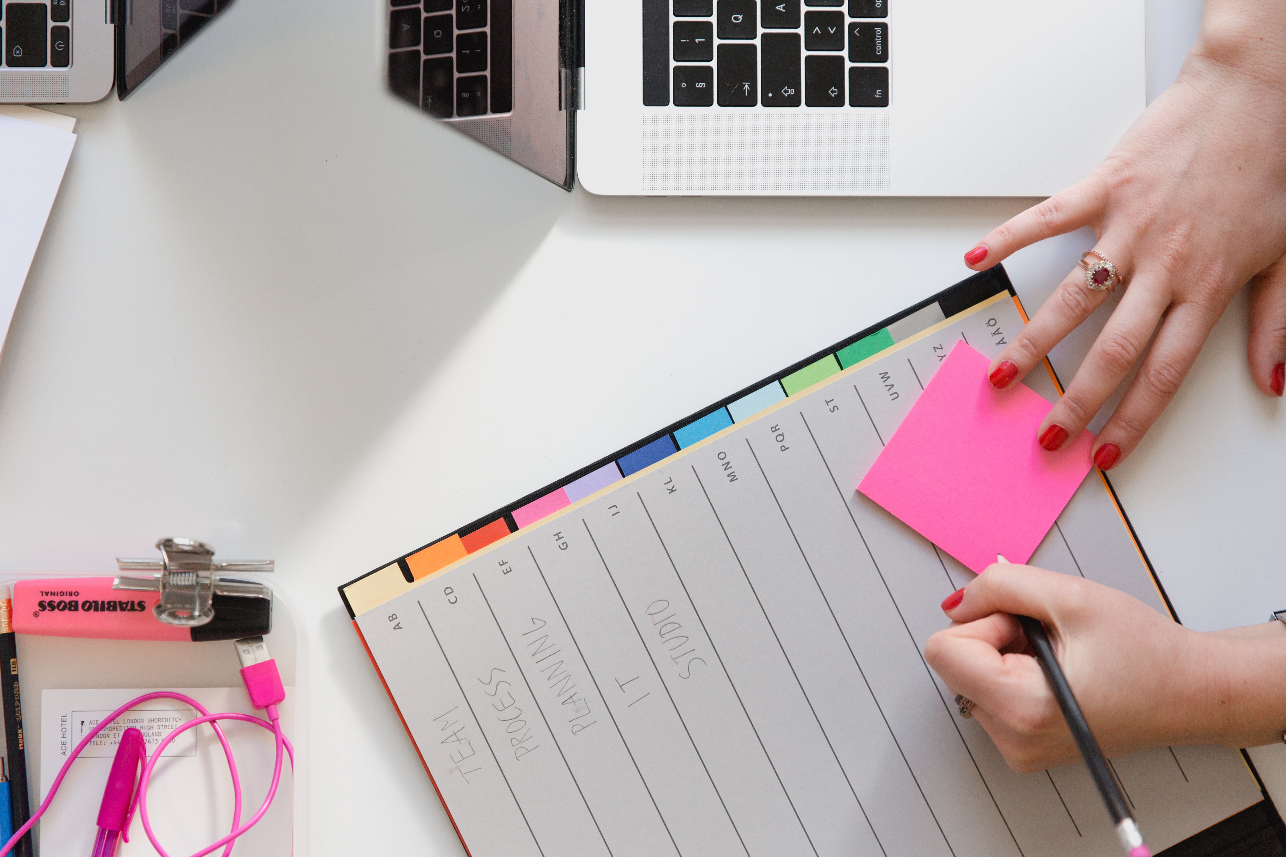 person holding pencil and stick note beside table Project Management Glossary of Terms